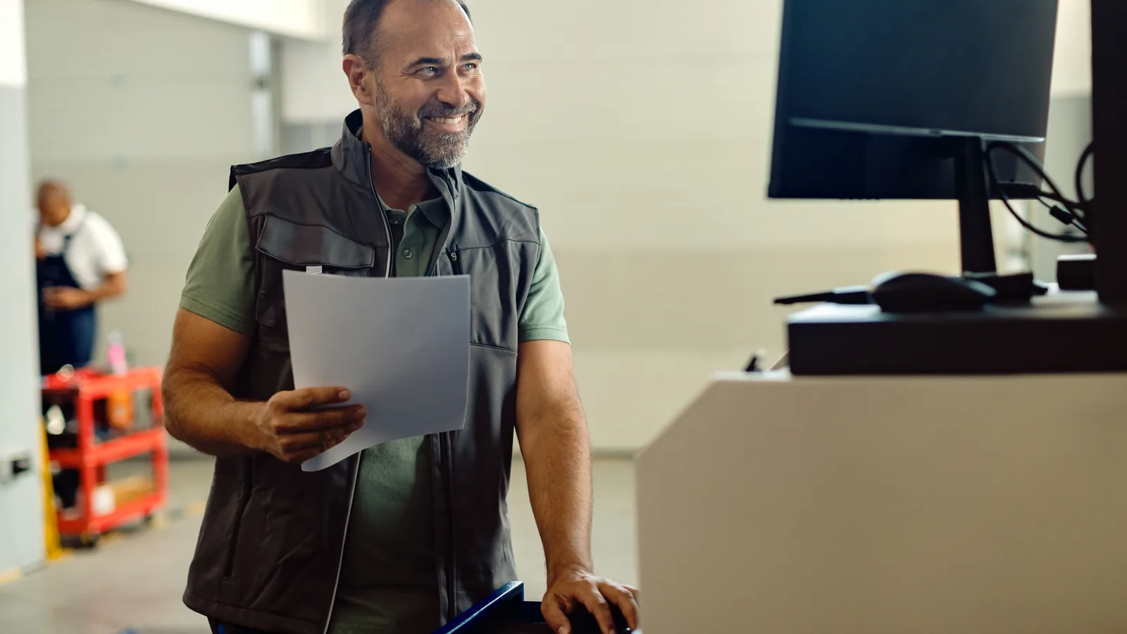 Un garagiste souriant consulte son ordinateur dans son atelier