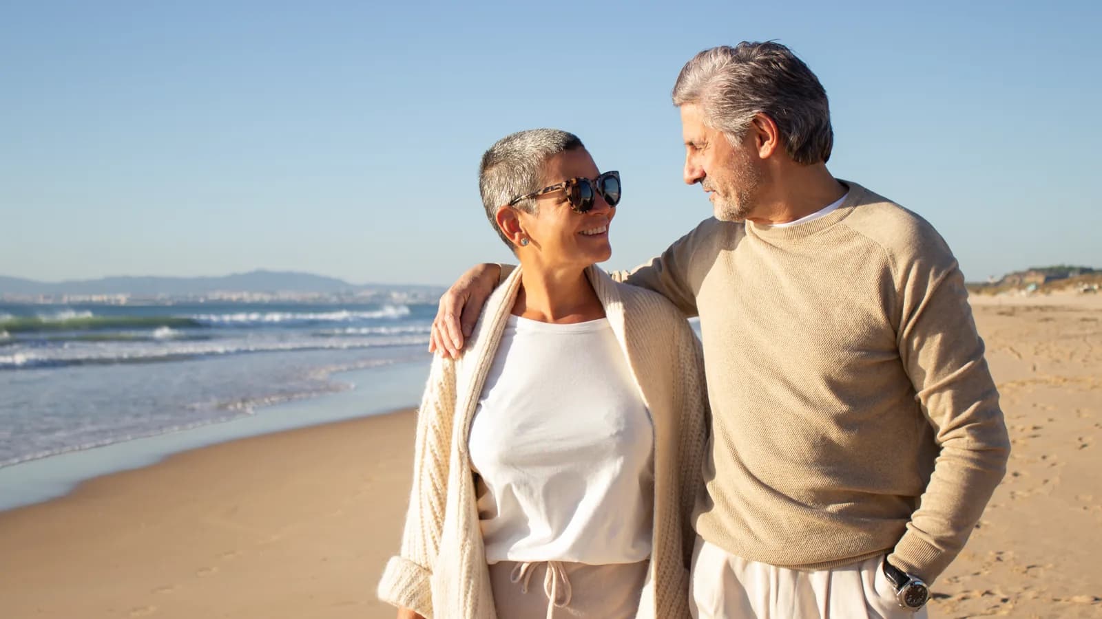 Un couple d'une soixantaine d'années marche au bord de la mer