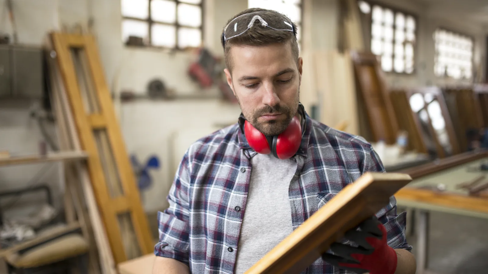 Un menuisier examine une pièce de bois dans son atelier
